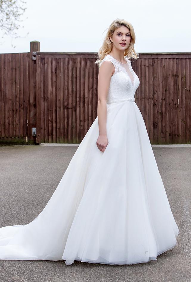 Side view of Tea length wedding dress with plunge lace illusion bodice and tulle skirt with pearl and bead waist detailing.