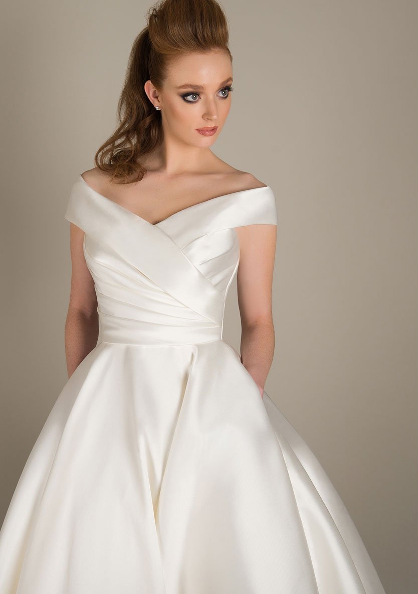 Deluxe Mikado wedding gown with dress with beautifully pleated bodice, wide neck line and full Mikado skirt with pockets completes this classic gown. Just beautiful! Also available in shorter tea and Fifties lengths.