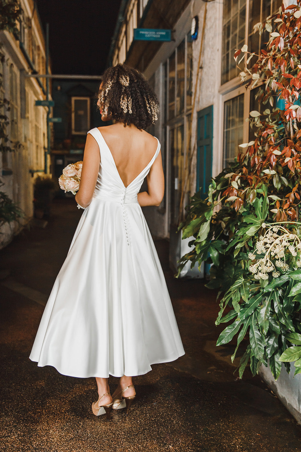 Back of the Marie tea length satin gown with pleats on bodice front & back. Dressed buttons over zip.