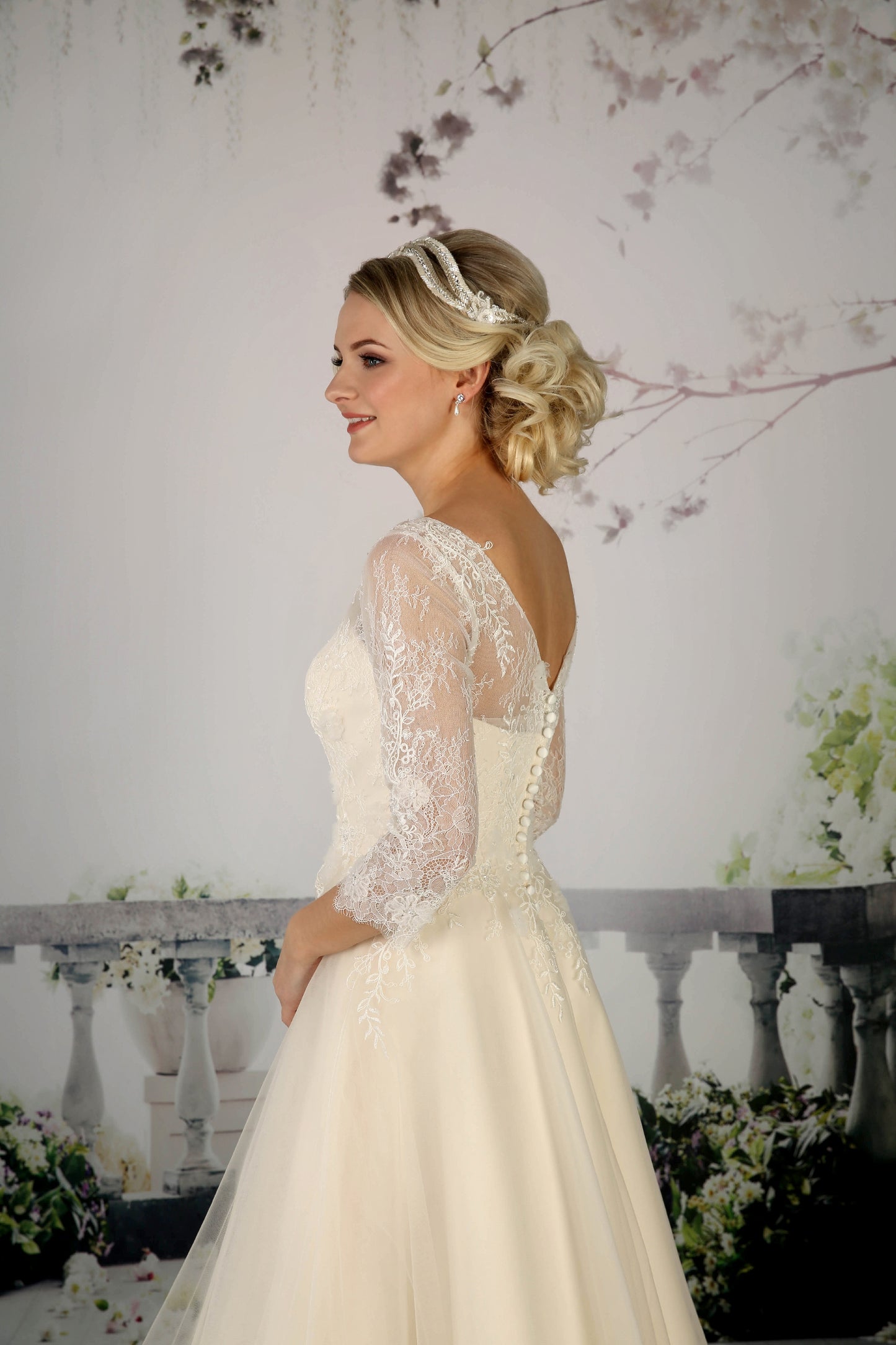 The pretty Cora tea-length bridal gown has a French and corded lace bodice with  illusion neckline and 3/4 length sleeves in champagne
