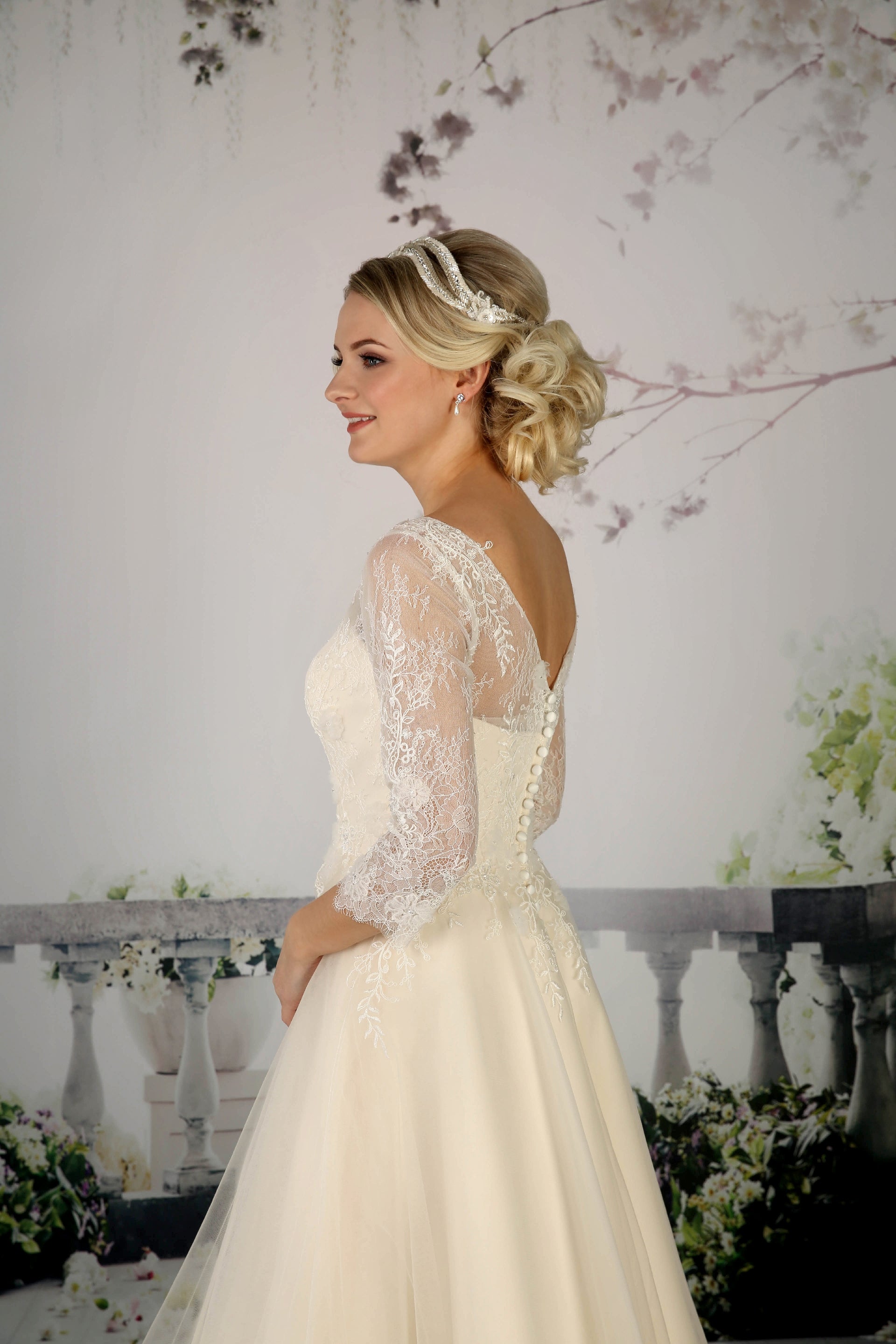 The pretty Cora tea-length bridal gown has a French and corded lace bodice with  illusion neckline and 3/4 length sleeves in champagne